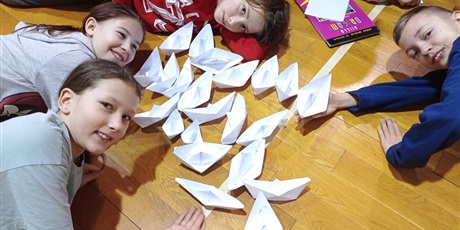 Powiększ grafikę: Uczniowie leżą wokół łódek z papieru